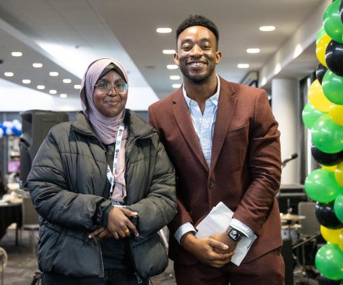 A girl stands smiling alongside a man in a suit