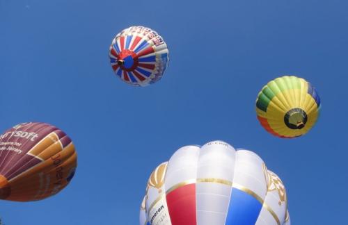 Hot air balloons ascend into a clear blue sky at Bristol Balloon Fiesta
