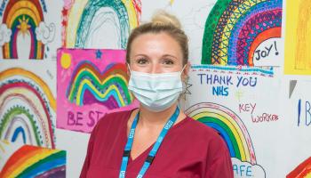 North Bristol NHS Trust staff member standing in front of a display of rainbow drawings