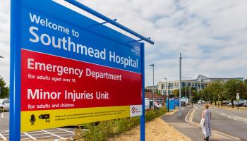 A blue, red and yellow sign saying "Welcome to Southmead Hospital" with information about the emergency department. The Brunel Building at Southmead Hospital can be seen in the background.