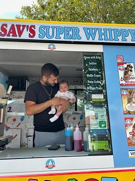 A man holds a baby inside an ice cream van