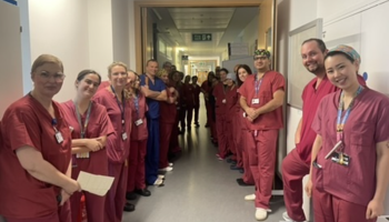 A photo of the theatre teams lined up on each side of a corridor in their scrubs.