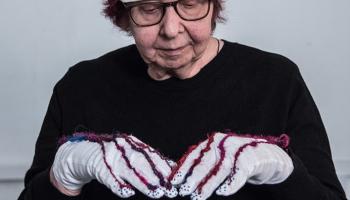 Women looking down with gloves with red string and a pink and white hat on 