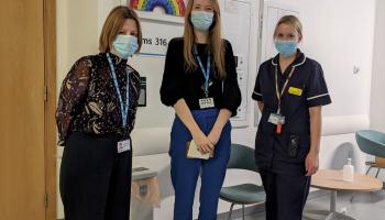 Chief Executive, Maria Kane, giving thank you cards to two staff members.