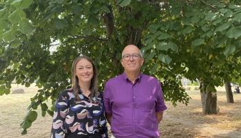 Two people stand in front of a tree