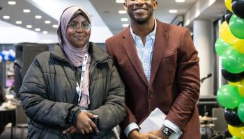 A girl stands smiling alongside a man in a suit