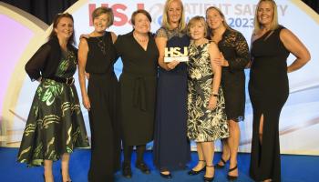 A group of seven people on stage collecting their awards at the HSJ award. They are all in formal dress and the person in the middle of the group is holding the HSJ award.