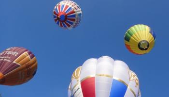 Hot air balloons ascend into a clear blue sky at Bristol Balloon Fiesta