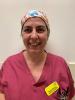 Karen Pereira Woman in raspberry-coloured scrubs and a theatre cap looking at the camera, smiling